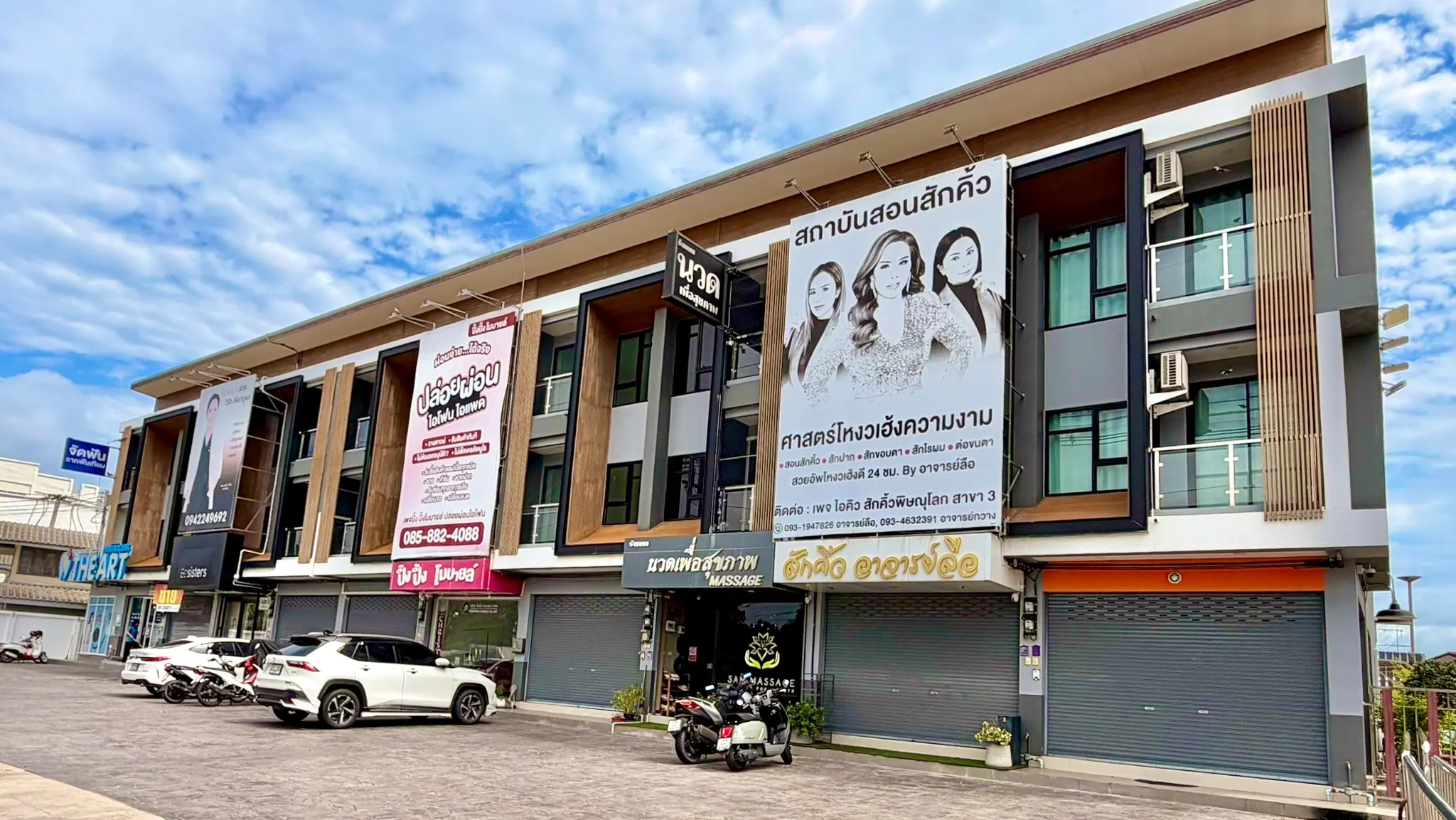 อาคารร้านแซมนวดเพื่อสุขภาพและลานจอดรถบริเวณหน้าร้านในเวลากลางวัน